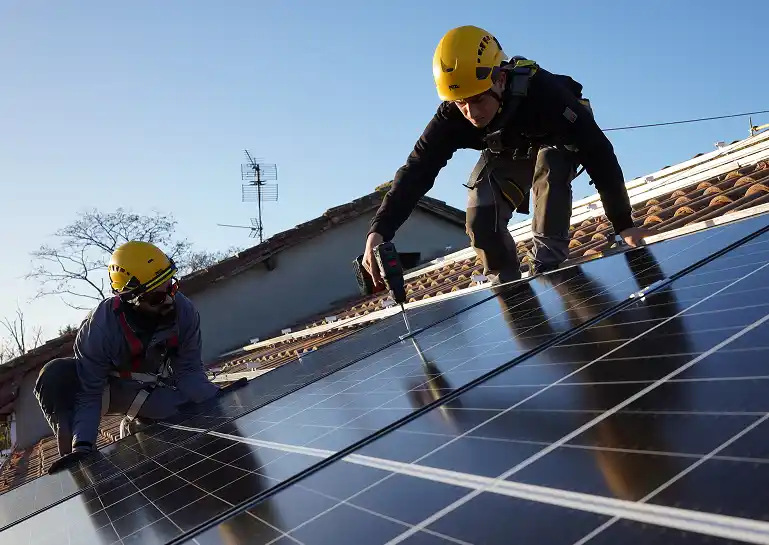 Casa con paneles solares en el tejado rodeada de una pradera de color verde